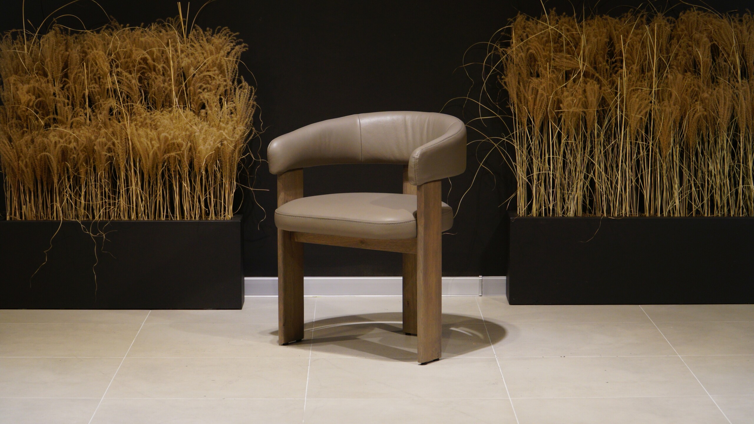 Designerskie krzesło dębowe Serena z naturalną skórą w beżowym odcieniu i charakterystycznym półokrągłym oparciem pełniącym funkcję podłokietników