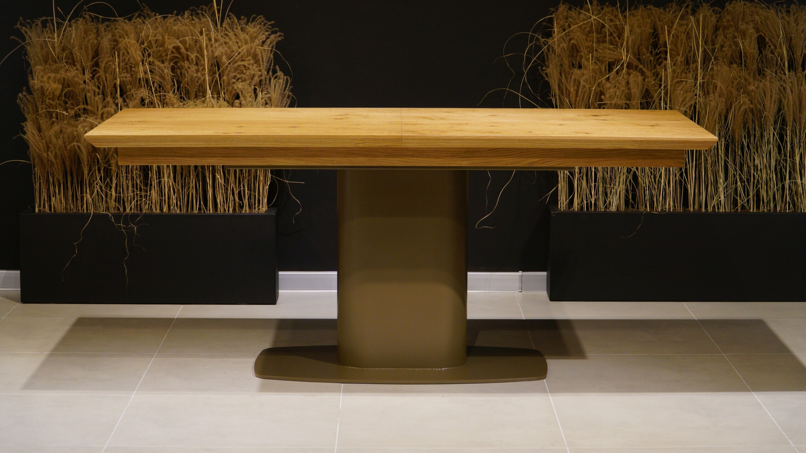 Elegancki stół do jadalni z naturalnym fornirem dębowym o wyraźnym usłojeniu oraz designerską nogą umieszczoną pośrodku blatu